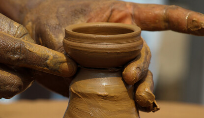 Hands of potter making clay diya/pot