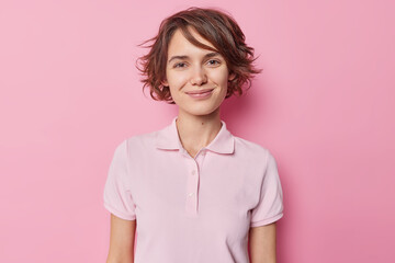 Portrait of good looking brunette woman smiles tenderly has charming look wears casual t shirt...