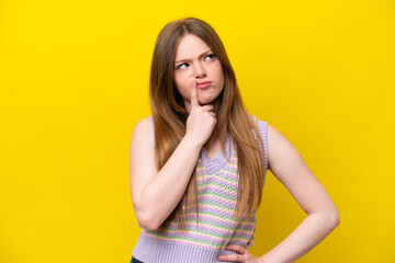 Fototapeta na wymiar Young caucasian woman isolated on yellow background having doubts while looking up