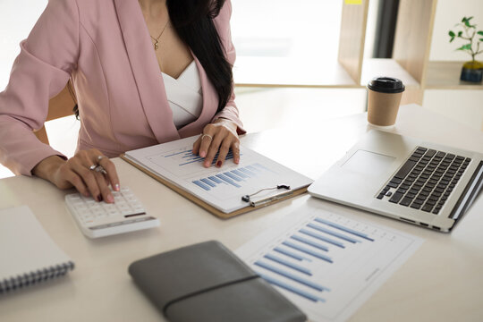 Businesswoman using calculator and laptop for do math finance on desk, tax, accounting, statistics and analytical research concept.