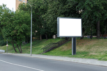 Blank horizontal large billboard in the city. Hill with green trees. Mock-up.