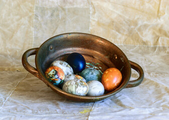 ancient copper bowl with colored eggs, celebration of Easter