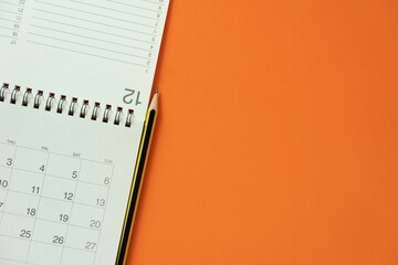 close up of calendar and pencil on the orange table background, planning for business meeting or...