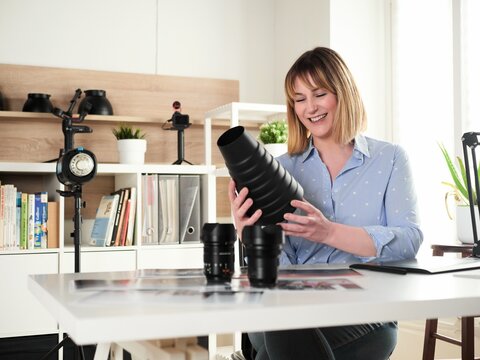 Female photographer working at office studio and holding a snoot reflector