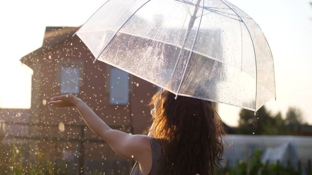 Happy young woman dancing and having fun with umbrella outdoor at sunny weather. slow motion