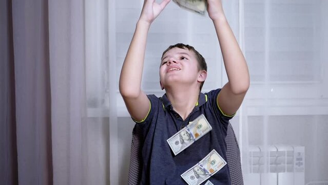 Happy Teenager Catching with Hands Falling 100 Dollar Bills Flying on his Head. Rich successful smiling boy millionaire. Scatter, throw money. Win, fortune. Earnings. Wages. Finance, wealth, capital.