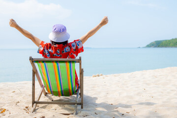 Summer beach vacation concept, Asia woman with hat relaxing and arm up on chair beach at Thailand