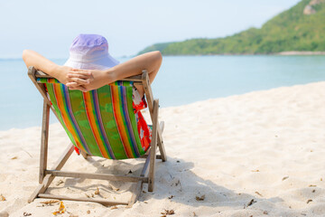 Summer beach vacation concept, Asia woman with hat relaxing and arm up on chair beach at Thailand