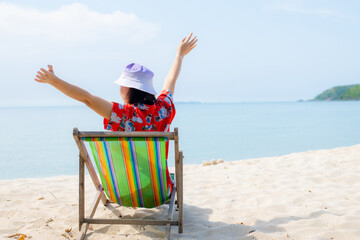 Summer beach vacation concept, Asia woman with hat relaxing and arm up on chair beach at Thailand