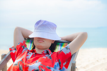 Summer beach vacation concept, Asia woman with hat relaxing and arm up on chair beach at Thailand