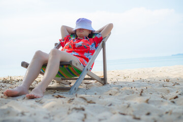 Summer beach vacation concept, Asia woman with hat relaxing and arm up on chair beach at Thailand