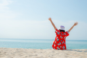 Happy traveller woman in red dress enjoys her tropical beach vacation