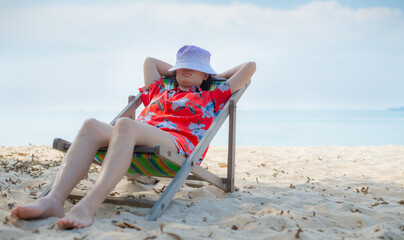 Fototapeta na wymiar Summer beach vacation concept, Asia woman with hat relaxing and arm up on chair beach at Thailand