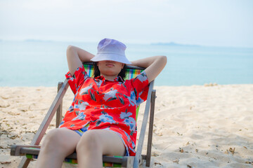Summer beach vacation concept, Asia woman with hat relaxing and arm up on chair beach at Thailand