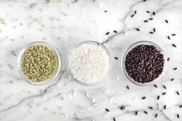 Three varieties of rice, green, white and black, in glass bowls
