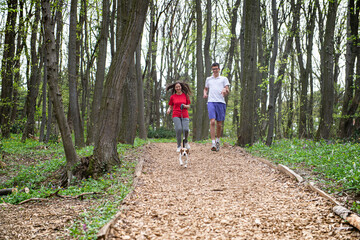 Obraz premium A young girl and a boy run through the woods with their dog Beagle