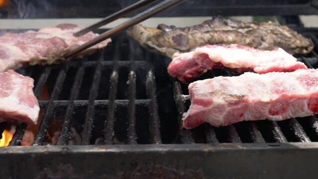 Slowmotion of cooking a delicious pork ribs over the fire on the BBQ grill. Cook pork meat on grilled meat. Food cooked with grilling barbecue in backyard of house