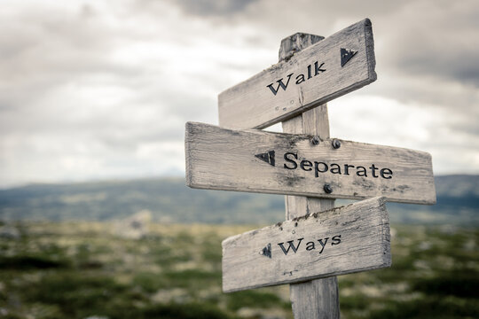 walk separate ways text quote written in wooden signpost outdoors in nature. Moody theme feeling.