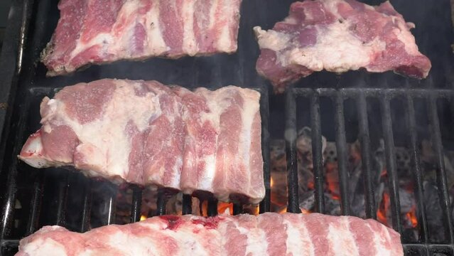 Slowmotion of cooking a delicious pork ribs over the fire on the BBQ grill. Cook pork meat on grilled meat. Food cooked with grilling barbecue in backyard of house
