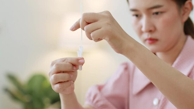 Young Asian woman using rapid antigen test kit (ATK) for self test at home. Pandemic of disease, covid-19, coronavirus