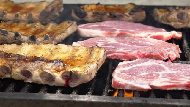 Slowmotion of chef cooking tasty ribs pork on a barbecue grill. Close up of delicious grilled pig cooked in BBQ of garden home at holiday vacations in Spain.