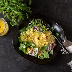 plate with salad with tuna, corn and pineapple on a dark table
