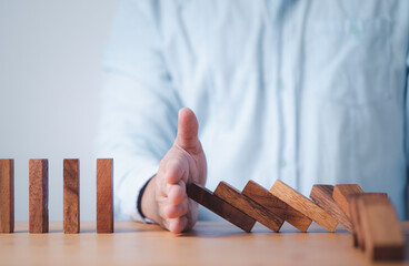 Businessman hand stop wooden block falling others block dominos for risk and crisis management...
