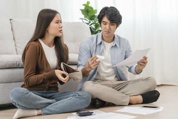 Stressed financial owe asian young couple love sitting suffer, stressed and confused by calculate expense from invoice or bill, no money to pay, mortgage or loan. Debt, bankrupt or bankruptcy people.