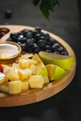 Wooden plate with fruits and nuts on a dark background. Fruit set on a black background