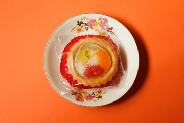 Fruit pie wrapped with transparent plastic on a plate
