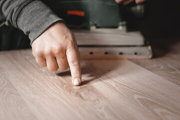 A carpenter works in a workshop. Joiner's grinders, furniture manufacturing. A carpenter is grinding a wooden part with an electric sander.