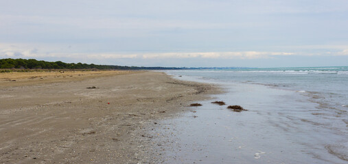 Marine landscape. Beach with dark sand with blue sky background. Brussa, Caorle, Italy.