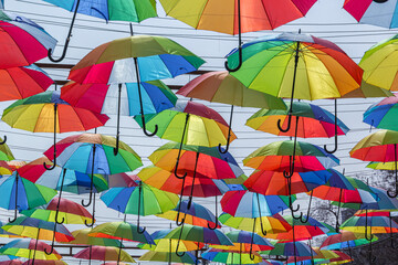 Fototapeta na wymiar Multi-colored umbrellas over a pedestrian street against the sky on a sunny day
