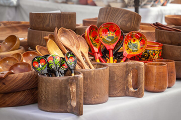 Wooden spoons and mugs with artistic painting on the counter of a street stall. Handmade