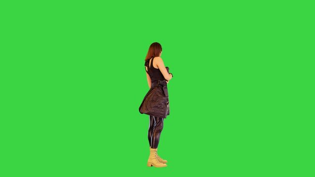 Girl in black tank top and leather skirt poses with a gun in hands, making yeah on a Green Screen, Chroma Key.