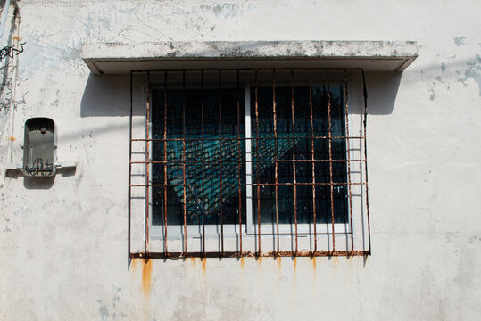 錆びた鉄格子の窓のある古いコンクリート作りの壁