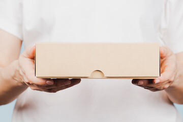 Woman hands holding brown ecological package box made of natural corrugated cardboard. Mockup...