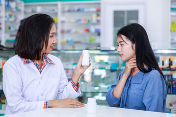 doctor female explains dispenses medicationa and gives advice to young asian women patients with sore throats in pharmacy