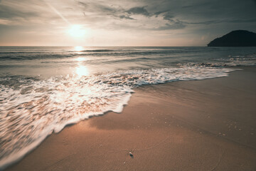 long exposure shot soft wave of the sea on the sandy beach at morning sunlight .