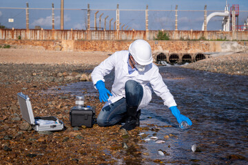 Scientist wearing safety uniform and glove under working water analysis and waste water quality to...