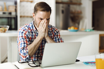 Worried mid adult man working on a computer at home