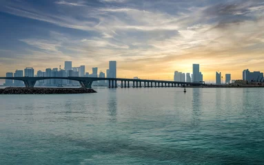 Gordijnen Abu Dhabi, Verenigde Arabische Emiraten - februari 2022: Panoramische skyline van Abu Dhabi met een brug tijdens zonsondergang. Abu Dhabi trekt jaarlijks 10 miljoen mensen. © CanYalicn