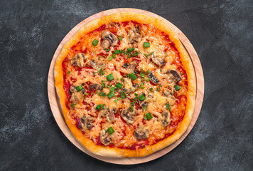 Pizza with vegetables, cheese and fresh herbs on a black background.