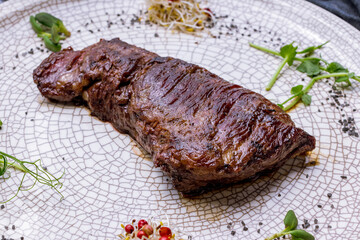 roast beef Steak machete on grey plate on dark stone table side view macro close up