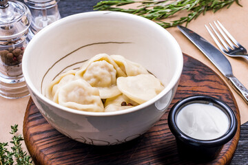 Dumplings with sour cream and herbs on wooden table