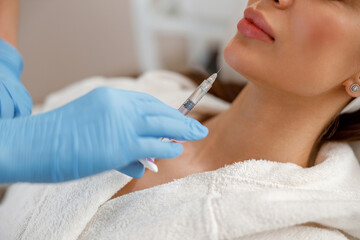 Closeup of young woman getting hyaluronic acid injections in chin at beauty salon. Cosmetology - obrazy, fototapety, plakaty