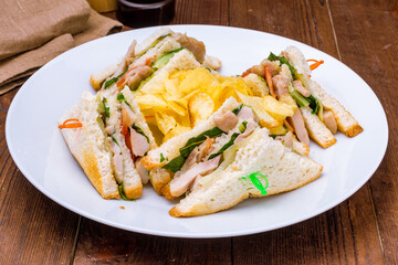 club sandwich with chicken, vegetables and chips on white plate