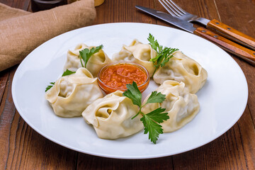 Manty with beef with tomato sauce on white plate