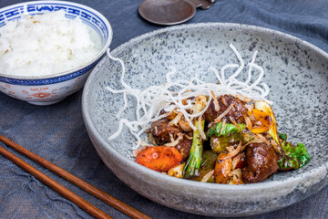 Beef with sliced vegetables on grey plate side view