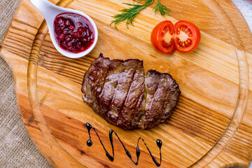 roast beef Steak with berry sauce on the board macro close up top view